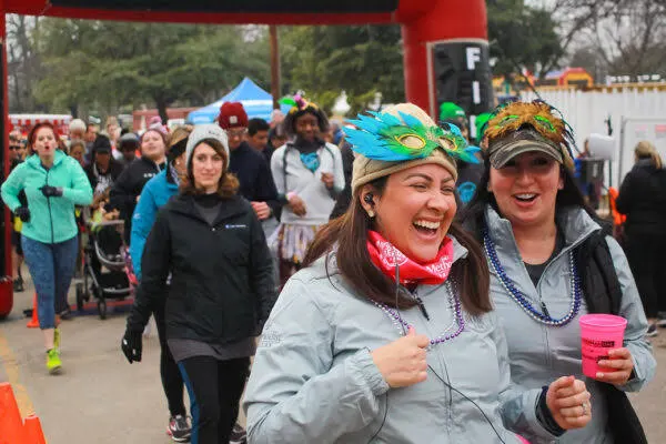 Two runners laughing in feathered masks